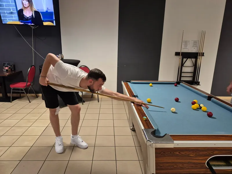 Un joueur vise une bille sur une table bleue